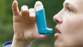 关闭使用哮喘吸入器的一个年轻人在公园