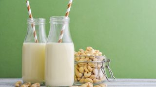 两瓶瓶与一个瓶子的腰果在绿色背景的腰果