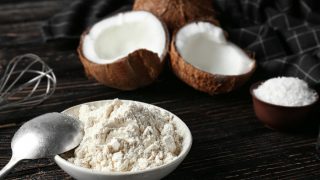 一碗椰子粉放在一个黑色平台上的椰子旁边