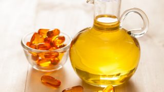 木桌上放着一罐鱼油和一碗鱼胶胶囊