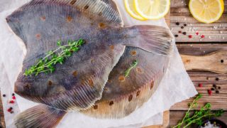 桌上有两条配着香草的比目鱼