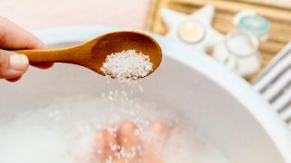 在脚浴水中添加盐与脚浸泡材料在背景中