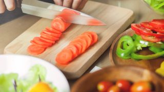 一名女子正在切胡萝卜，准备制作釉面胡萝卜食谱