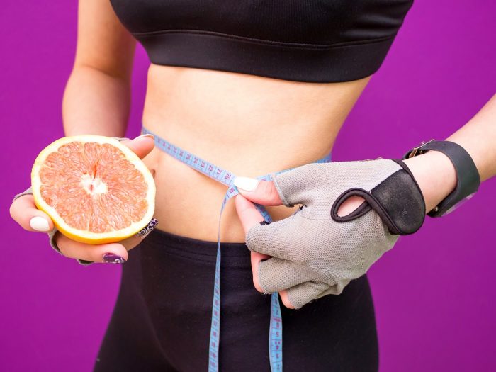 一只手拿一个葡萄柚，另一只手量腰围