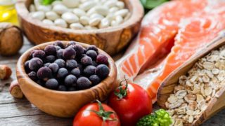 木柜台上放着三文鱼、燕麦、浆果、坚果和西红柿等健康食品