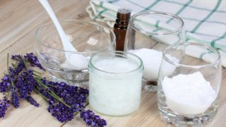 三碗白色粉末，精油瓶，蜡和薰衣草花在木质表面。
