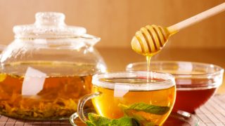 蜂蜜被倒进一杯茶里，薄荷和水壶，背景是一杯茶。