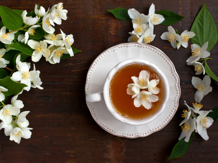 茉莉花茶的杯子在茶碟，与它旁边的新鲜茉莉花
