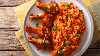 与炸鸡翼的jollof米在一块板材的特写镜头在黄色餐巾