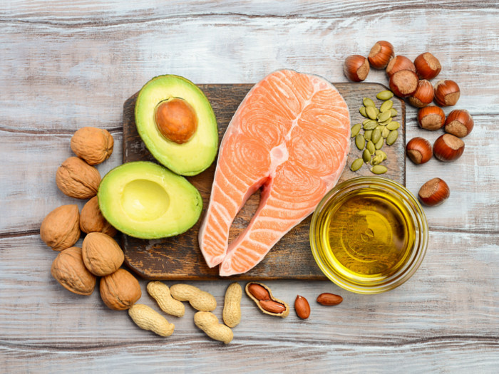 一个鱼排的切片鳄梨，不同类型的螺母和的油的玻璃的Flatlay图片。