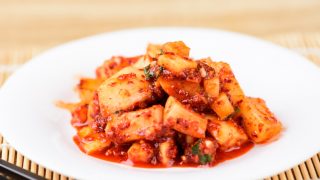 萝卜kimchi射击的关闭在有筷子的一块白色板材