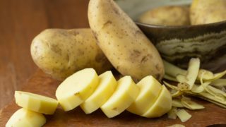 木制背景上带皮的整片和切片土豆