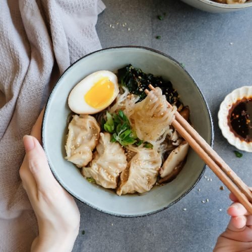 一个人用筷子吃白泷汤面和日式煎饺