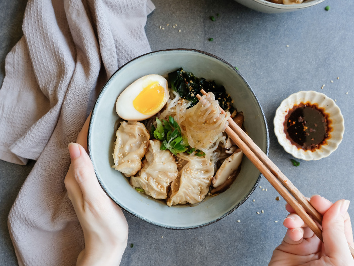 一个人用筷子吃白泷汤面和日式煎饺