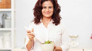 Shonali Sabherwal，大性蛋白营养师＆厨师，拿着沙拉碗在她的手上和看照相机