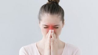 一个有眼睛的女孩闭上揉搓她的红色鼻子