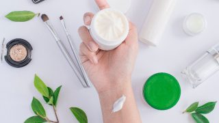 一只手拿着一个白色背景下的奶油小容器