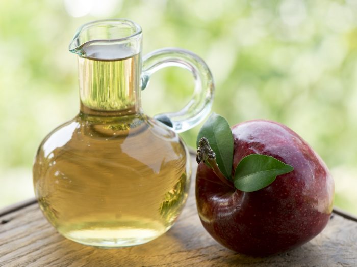 一个整个新鲜的苹果，与一罐苹果汁或苹果醋在桌子上