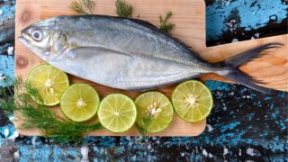 平面画的鲹鱼放置在木板与石灰一半和小枝莳萝。