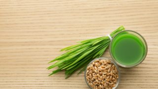 小酌一杯麦草汁，木桌上放一碗谷物和豆芽